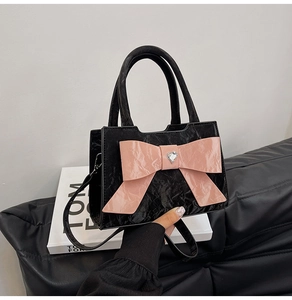 Detail of glossy pleated leather handbag with large pink bow and heart gemstone