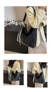 Detail of black vintage texture hobo bag featuring a white lace bow tie decoration