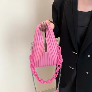 Detail of bright pink pleated PU handbag with acrylic chain handle and metal strap