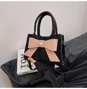 Close-up of black pleated texture with pink patent bow and heart crystal on the handbag