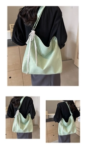 Detail view of a green bucket bag featuring a white lace bow and wide shoulder strap