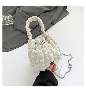 Macro view of white pleated cloud bucket bag with textured fabric and drawstring detail
