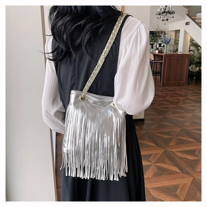 Détail d'un sac à bandoulière argenté avec franges métalliques et chaîne dorée