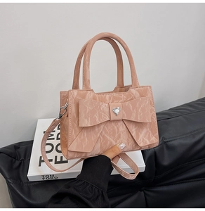 Detailed shot of pink leather handbag with large bow and heart-shaped crystal on a sofa