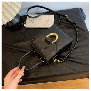 Detail of black lychee grain leather mini bag with gold D-shaped buckle and top handle