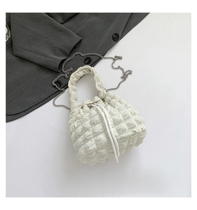 Detail of white bubble textured bucket bag with drawstring closure and silver chain strap