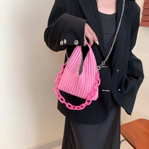 Detail of pink pleated PU shoulder bag with dual resin and metal chains on a model