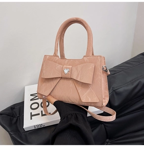 Detail of soft pink glossy textured bag with large bow and heart rhinestone accent