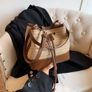 Détail du sac seau en paille tressée avec bordure en cuir marron et cordon serrage