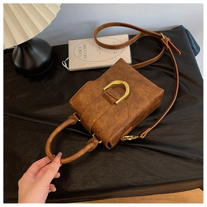 Detail of vintage brown leather handbag with golden D-ring buckle and textured finish