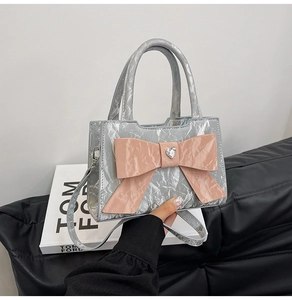 Detail of silver crinkled leather bag with pink bow and heart-shaped crystal decor