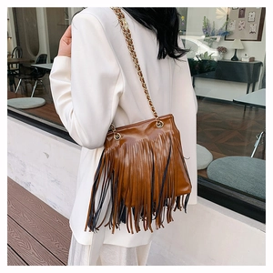 Détail d'un sac à bandoulière en cuir marron à franges avec chaîne en métal doré brillant