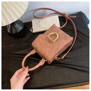 Detail of vintage dusty pink square handbag with matte gold D-ring buckle and leather texture