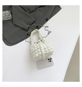 Detail view of white ruched cloud bucket bag with metal chain strap and drawstring closure