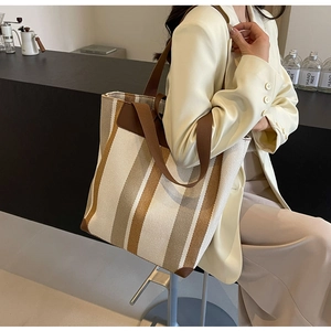 Detailed view of large canvas tote bag with brown stripes and leather handles