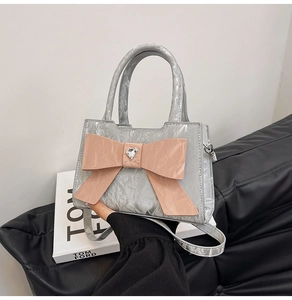 Close-up of silver wrinkled leather handbag with pink bow and heart crystal detail