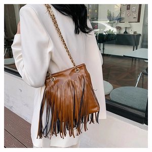 Vue détaillée du sac à franges marron avec chaîne dorée porté par un mannequin chic