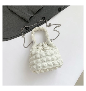 Detail view of cream pleated bucket bag with bubble texture fabric and metal chain strap