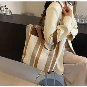 Detail of the large canvas tote bag with brown leather trim and striped pattern on shoulder