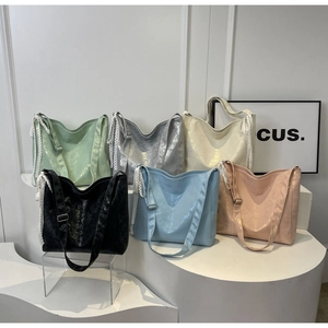 Detail view of large bucket bags featuring glossy wrinkled fabric and side lace bows