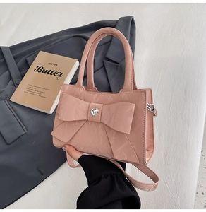 Detailed view of pink glossy handbag with oversized bow and sparkling heart rhinestone