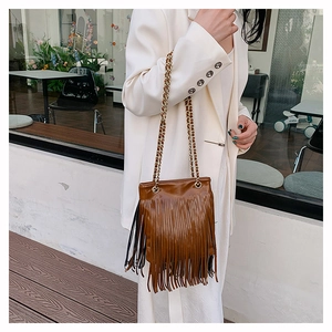 Détail du sac à bandoulière marron à franges avec chaîne dorée portée par un modèle