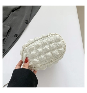 Detail of off-white pleated bubble textured cloud bag with a delicate metal chain strap