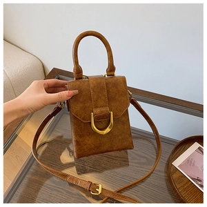 Detail of vintage brown textured leather handbag with elegant golden U-shaped metal clasp