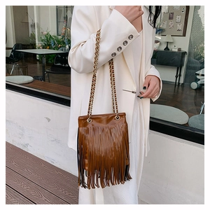 Détail d'un sac en cuir marron brillant avec de longues franges et chaîne dorée