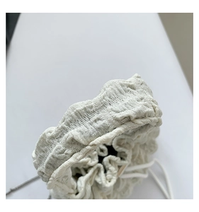 Detail of cream pleated cloud bag texture with soft fabric ripples and white drawstring