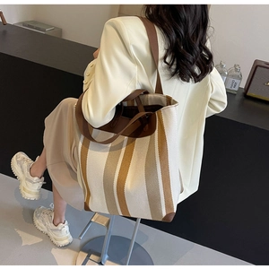 Detail of color-block striped canvas tote bag with brown leather trim and handles