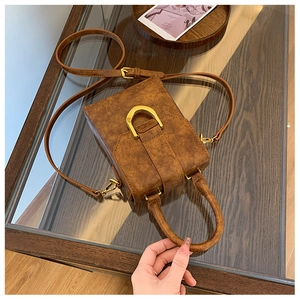 Top view of brown leather crossbody bag with gold hardware on a wooden table