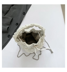 Macro shot of white pleated cloud bucket bag featuring silver chain and interior lining