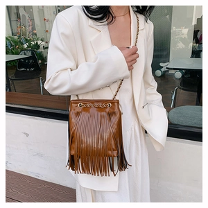 Gros plan d'un sac seau marron caramel à franges avec bandoulière en chaîne métal