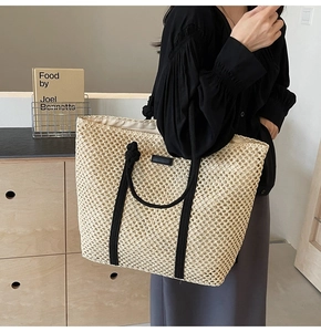 Close-up of the woven hollow texture and black rope handle on the straw tote bag