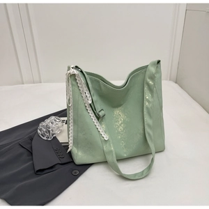 Detail of light green bucket bag with gold print patterns and white lace tassel ornament