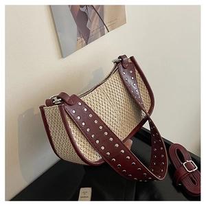 Détail du sac tissé avec bordure en cuir bordeaux et clous argentés sur la large bandoulière