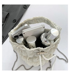 Top view of cream ruched bucket bag showing capacity for phones and cosmetics with chain strap