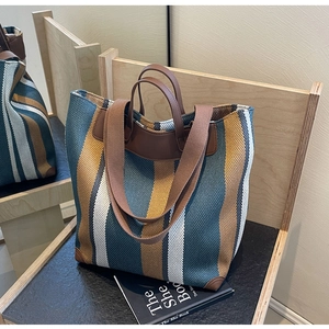 Detail of striped canvas tote bag showing textured weave and leather shoulder strap