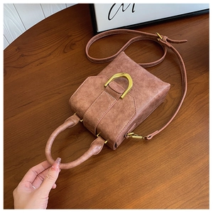 Detail view of vintage brown leather handbag featuring a golden D-shaped metal buckle accent
