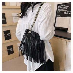 Détail des longues franges et de la bandoulière en chaîne de ce sac fourre-tout noir