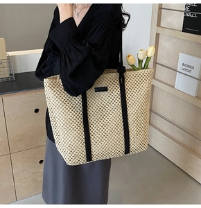 Close-up of a woven tote bag with black straps and interior tulip decor for beach vacations