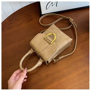 Detail view of khaki crossbody bag featuring vintage pleated texture and gold U-shaped hardware