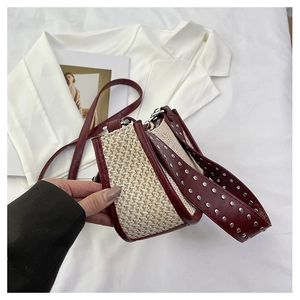 Détail du sac croissant tissé avec rivets argentés et finitions en cuir rouge