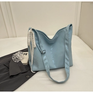 Detail of light blue bucket bag featuring glossy leather and a white lace ribbon accent