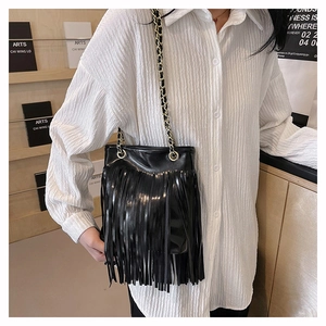 Détail de ce sac à bandoulière en cuir noir à franges avec chaîne dorée sur un mannequin