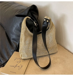 Detail of hand-woven straw shoulder bag with black PU leather strap and metal studs