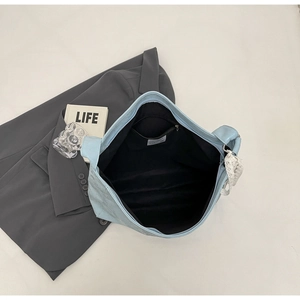 Detail view of the spacious light blue shoulder bag interior with black lining and zip pocket