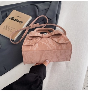 Detailed close-up of pink embossed leather bag featuring a large bow and heart rhinestone