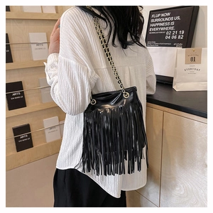 Détail d'un sac à bandoulière noir à franges avec chaîne porté par un mannequin